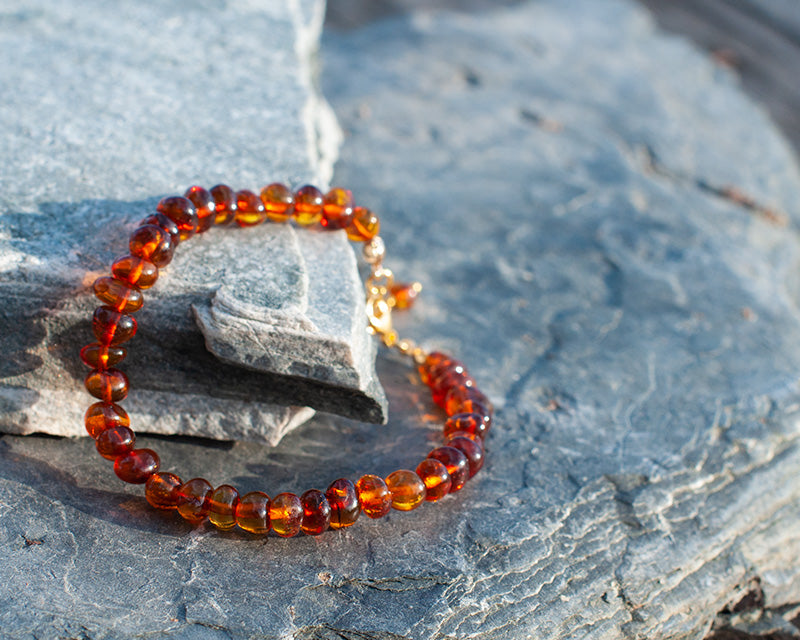 A goldplated Bylga bracelet laying on a rock in the sun.