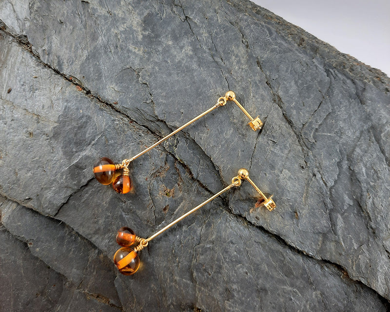 A pair of goldplated Duva earrings laying on a rock