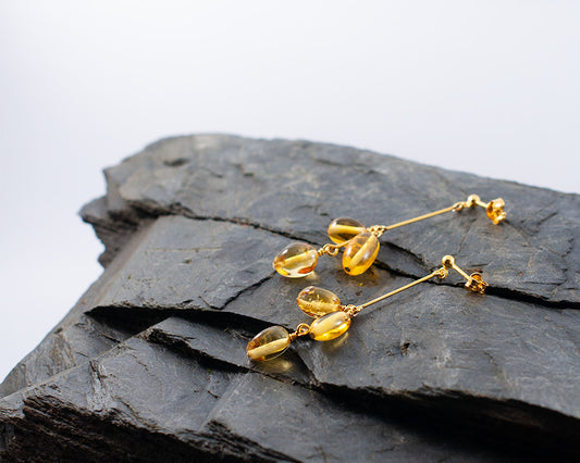 A pair of Himminglava goldplated earrings laying on a rock.