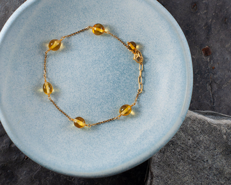 Sjavn goldplated bracelet in a blue ceramic bowl. picture taken from above.